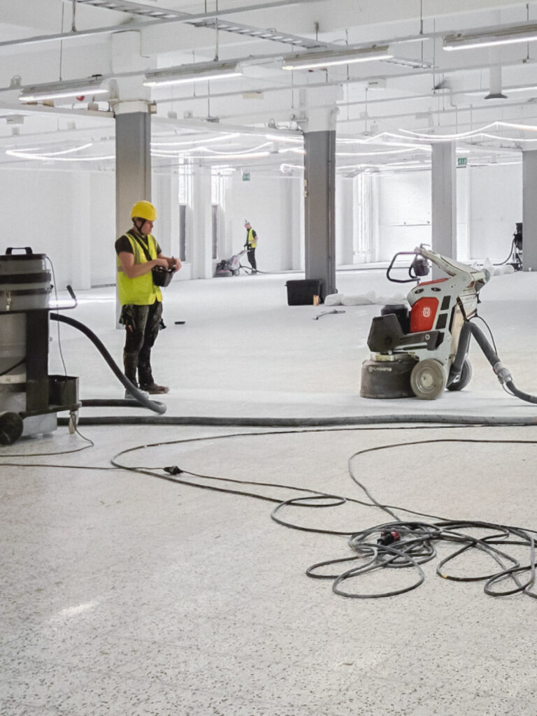 ihminen kiillottamassa betonilattiaa avarassa tilassa