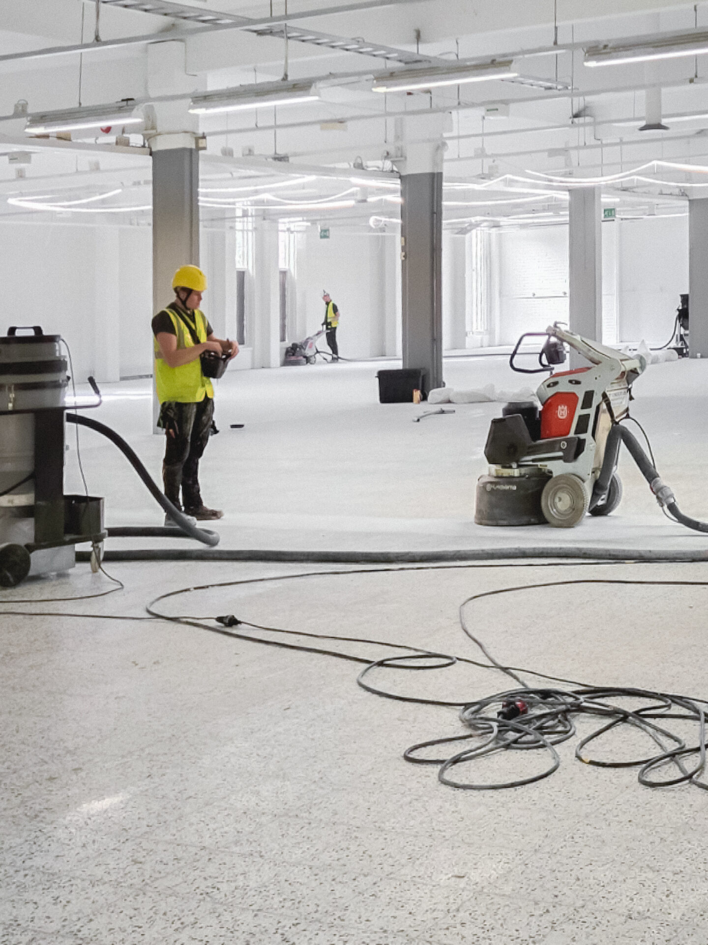 ihminen kiillottamassa betonilattiaa avarassa tilassa